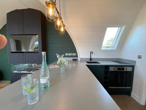 a kitchen with a counter with two bottles and glasses at POD St Ives - LUXURY GLAMPING ACCOMMODATION in St Ives