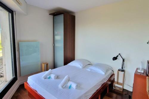 - une chambre avec un lit doté de draps blancs et d'oreillers bleus dans l'établissement Duplex double terrasses 4P, à Paris