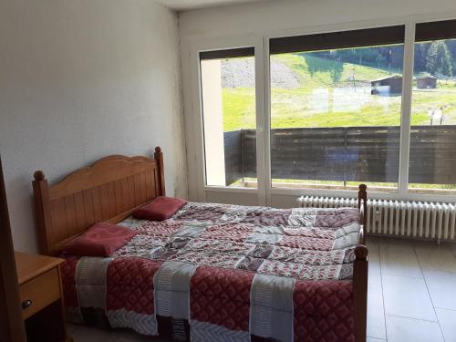 une chambre avec un lit et une grande fenêtre dans l'établissement Appartement Collet d'Allevard, à Allevard