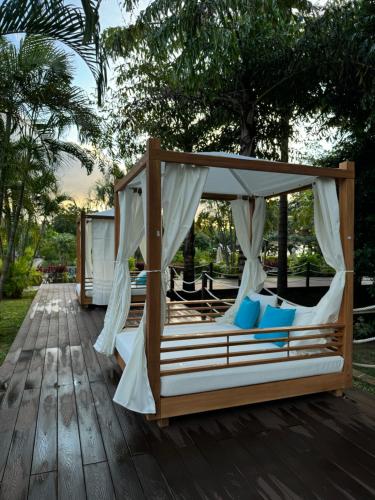 a canopy bed with blue pillows on a wooden deck at Savoy Seychelles Resort & Spa in Beau Vallon
