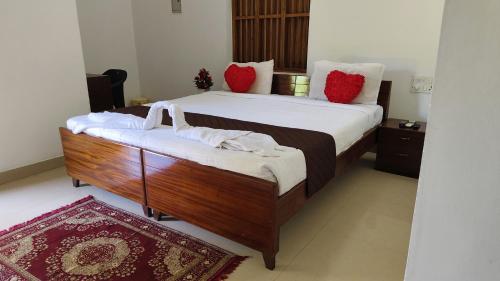 a bedroom with a large bed with white sheets and red pillows at Rithu Beach Villa in Alleppey