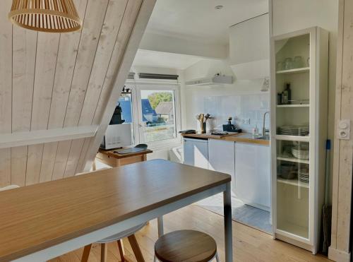 une cuisine avec des armoires blanches et une table en bois dans l'établissement Le Central - Studio avec vue mer, à Langrune-sur-Mer