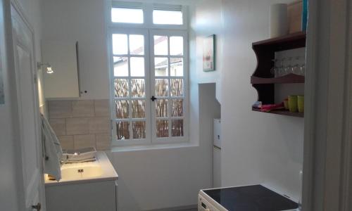 cocina blanca con fregadero y ventana en L'appartement d'Aymar, en Moulins