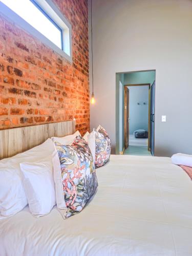 a bedroom with a brick wall and a bed with pillows at Highland Peace Haven In Dullstroom in Dullstroom