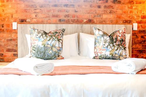 a white bed with pillows and a brick wall at Highland Peace Haven In Dullstroom in Dullstroom