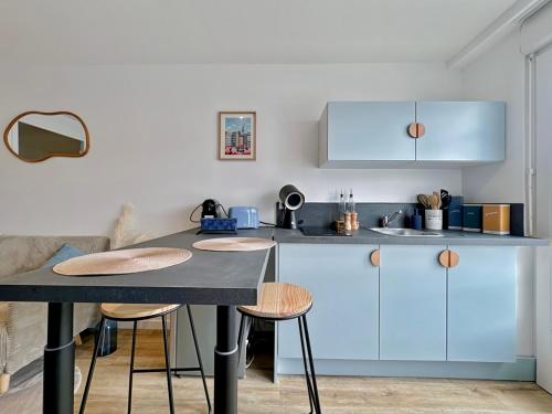 une cuisine avec des placards bleus et une table avec des tabourets dans l'établissement Appartement rénové et Modern proche Saint-Malo, à Saint-Jouan-des-Guérets