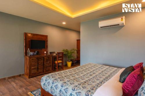 a bedroom with a bed and a tv and a desk at StayVista at Wildwoods Stone with Pool, Bathtub, Wi-Fi in Sawāi Mādhopur