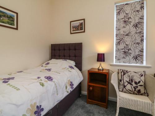 a bedroom with a bed and a chair and a window at Barton Lodge in Minehead
