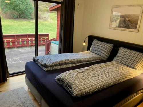 two beds in a room with a large window at Nice House by the Sea with private beach and jetty in Hjelmeland