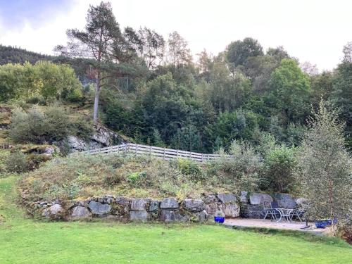 a garden with a bench and a stone wall at Nice House by the Sea with private beach and jetty in Hjelmeland