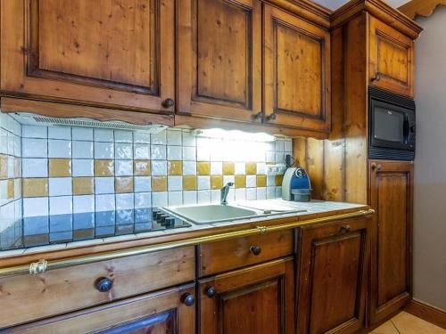 une cuisine avec des armoires en bois et un évier dans l'établissement Appartement charmant avec balcon, piscine & parking à Plagne Aime 2000 - FR-1-351-137, à Aime La Plagne
