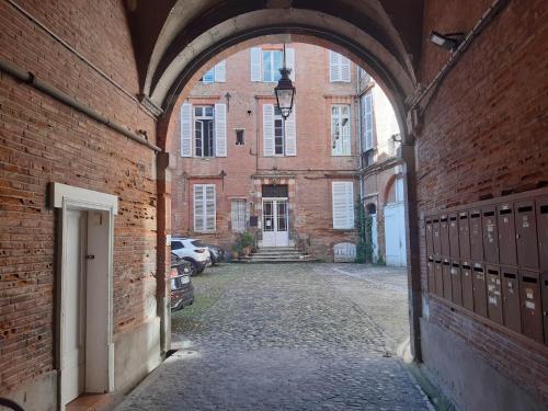 Une allée dans un bâtiment en briques avec une arche dans l'établissement Appartement centre Toulouse, à Toulouse