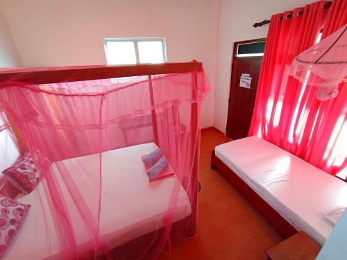 a bedroom with two bunk beds with red curtains at Pearl Deluna Resort Mirissa in Mirissa