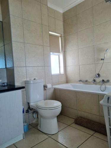 a bathroom with a white toilet and a bath tub at Point Village Accommodation - Stephen in Mossel Bay