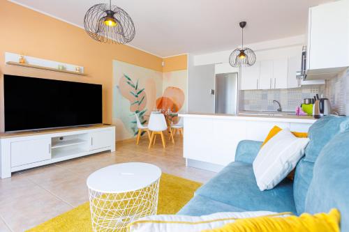 a living room with a blue couch and a kitchen at Las Rocas 115 - Fuerteventura Golf Club in La Guirra