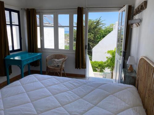 a bedroom with a bed and a desk and a window at Villa bohème chic à Sauzon avec vue mer et wifi - FR-1-418-174 in Sauzon
