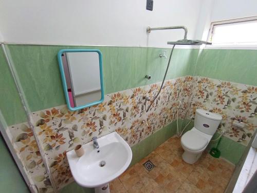a bathroom with a sink and a toilet and a mirror at Pearl Deluna Resort Mirissa in Mirissa
