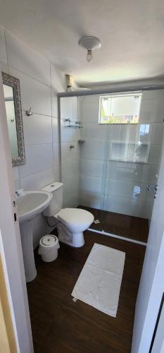 a white bathroom with a toilet and a sink at Residencial Marcelo e Irene in Florianópolis