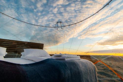 a bed in the middle of the desert with the sky at Aurora Igloo South in Hella
