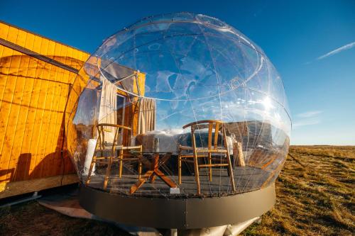 a glass ball with chairs in it next to a building at Aurora Igloo South in Hella