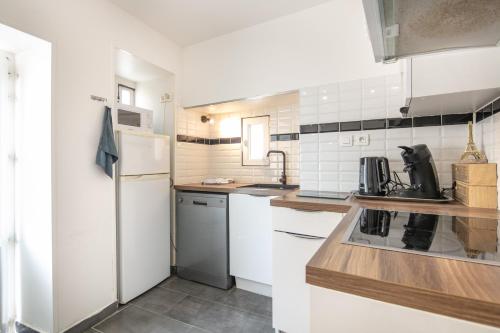 Il comprend une cuisine équipée d'appareils électroménagers blancs et d'un réfrigérateur blanc. dans l'établissement Le Saint-Geoirien - Duplex pour 4, à Merlas