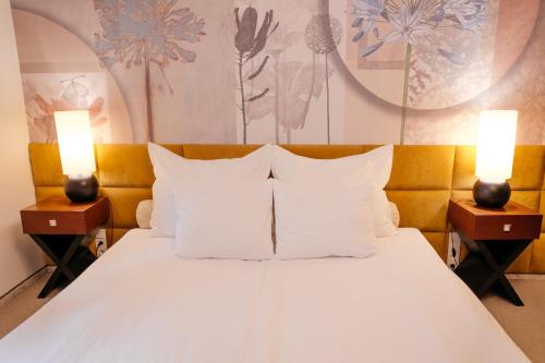a bed with white pillows and two lights on tables at Vanilla Hotel in Lublin