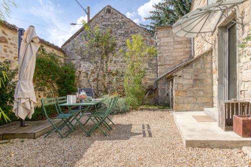 a patio with a table and an umbrella at Les Gîtes de l'Atelier - Gîtes de charme en Forêt de Fontainebleau in Saint-Martin-en-Bière