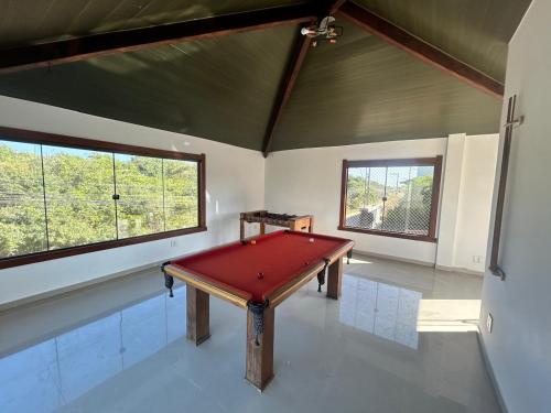 a ping pong table in a room with two windows at Casa Praia Marina Búzios in Búzios