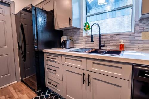Una cocina con gabinetes blancos y un refrigerador negro. en Home with Huge Fenced Yard, en San Antonio