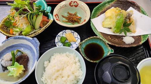 a table topped with plates of food and rice at ターミナホテル東予 in Nyūgawa