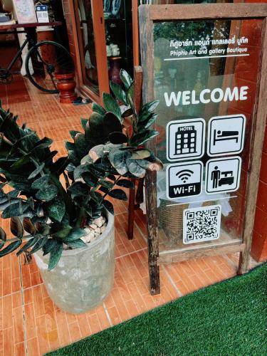 a welcome sign in a store with a potted plant at Phiphu Art and Gallery Boutique Sukhothai in Sukhothai