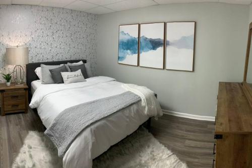 a bedroom with a white bed with two pictures on the wall at Panoramic Sunset View Waterfront Firepit in Cadiz