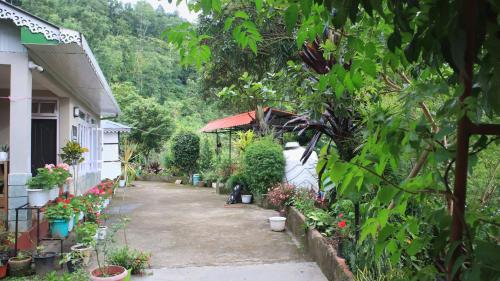 a person sitting in a garden next to a house at Hyangla Namsha Retreat in Soreng