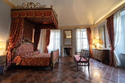 a bedroom with a canopy bed and a chair at Foresteria del Castello di San Giorgio Canavese in San Giorgio Canavese