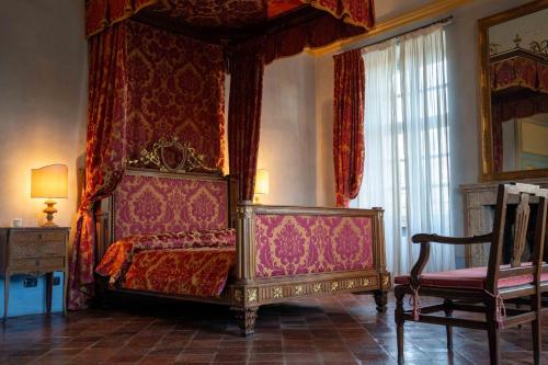 a bedroom with a canopy bed and a chair at Foresteria del Castello di San Giorgio Canavese in San Giorgio Canavese
