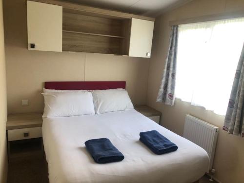 Un dormitorio con una cama con dos toallas azules encima. en Cute caravan Whitecliff Bay, en Bembridge