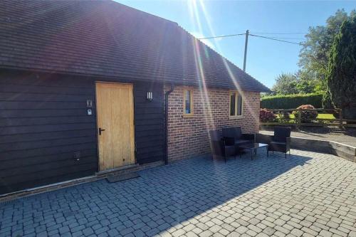 a brick building with a door and a table and chairs at 1 Coopers Cottage, Bodiam, East Sussex in Bodiam