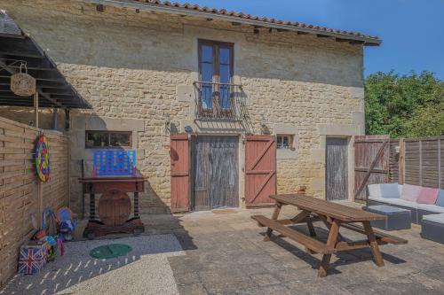 a patio with a wooden bench and a building at L'Olivier Gite in Lizant