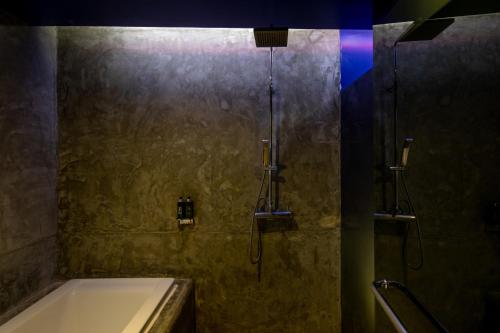 a bathroom with a shower with a tub and a sink at The Yama Hotel Phuket in Kata Beach
