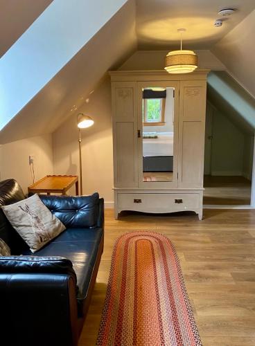 a living room with a black couch and a window at Highland Rooms - Room Only No Breakfast in Ullapool