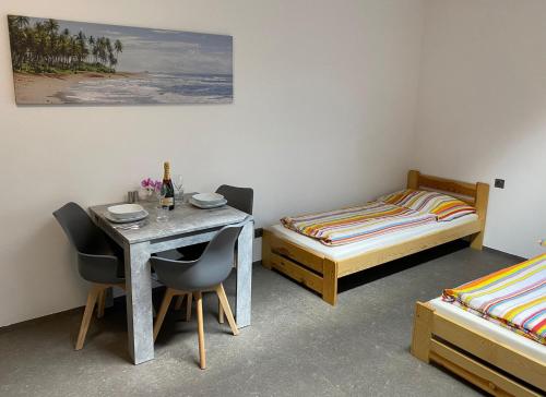 a room with a table and two beds and a table and chairs at JK Apartmány in Bělkovice