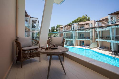 a balcony with a table and chairs and a pool at Eden Roc Resort - All Inclusive in Kallithea Rhodes