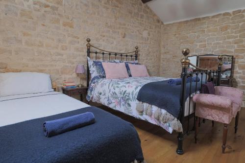 a bedroom with two beds and a brick wall at L'Olivier Gite in Lizant