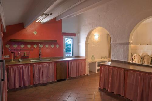 a large kitchen with red walls and wooden counters at Agroturismo Matxani Gran in Sant Climent