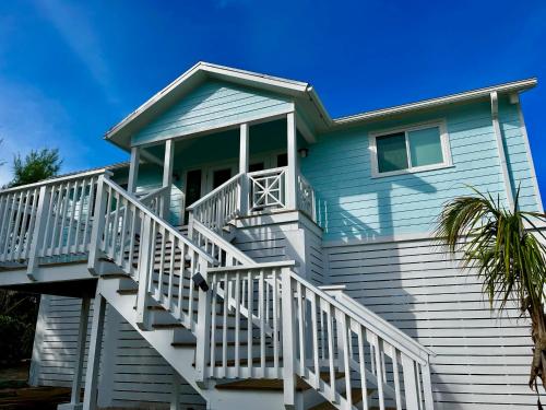 a blue house with white stairs and a palm tree at Sea Salt Bahamas on Great Guana Cay in Great Guana Cay
