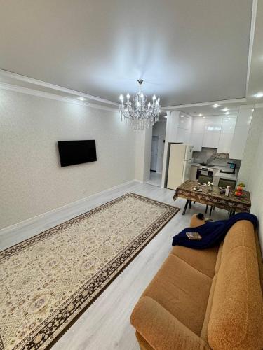 a living room with a couch and a table and a television at Гармония стиля in Aktau