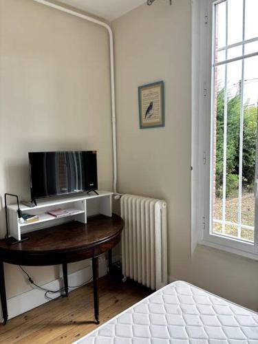 Cette chambre dispose d'une télévision, d'une table et d'une fenêtre. dans l'établissement Studio Jardin à la Villa Odette, à Toulouse