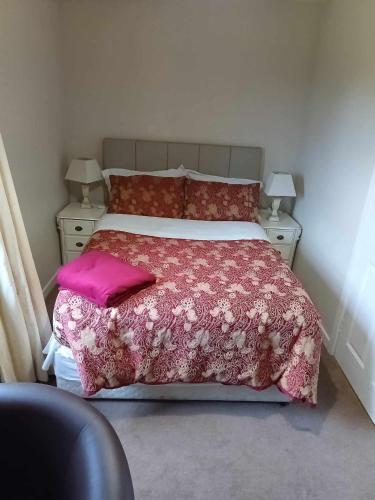 a bedroom with a bed with a pink comforter and pillows at Pinewood Lodge Guest House in Omagh