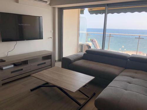 un salon avec un canapé, une télévision et une table dans l'établissement Eros, à Nice