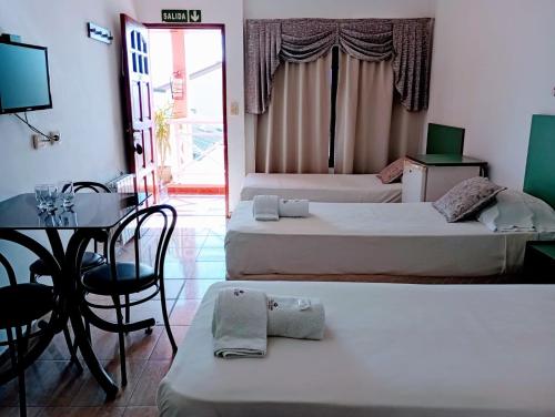 two beds in a room with a table and a desk at Apart Hotel Guarumba in Federación